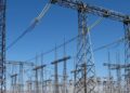 High-voltage switchgear and overhead lines at an electrical substation under a blue sky