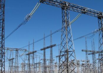 High-voltage switchgear and overhead lines at an electrical substation under a blue sky