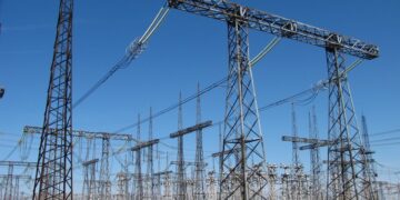 High-voltage switchgear and overhead lines at an electrical substation under a blue sky