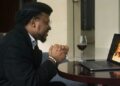 Man smiling on a video call date with a woman on his laptop, glass of red wine on the table
