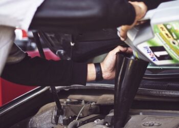 Mechanic topping up engine oil under a car bonnet