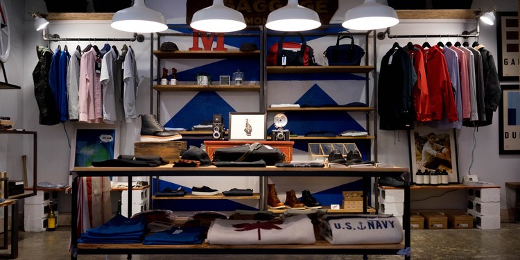 Clothing and accessories displayed on shelves in a small retail store